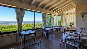 Comedor con vistas a un viñedo, vigas de madera en el techo y una mesa con sillas.