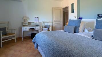 A bedroom with a bed, a desk, a chair, and a door.