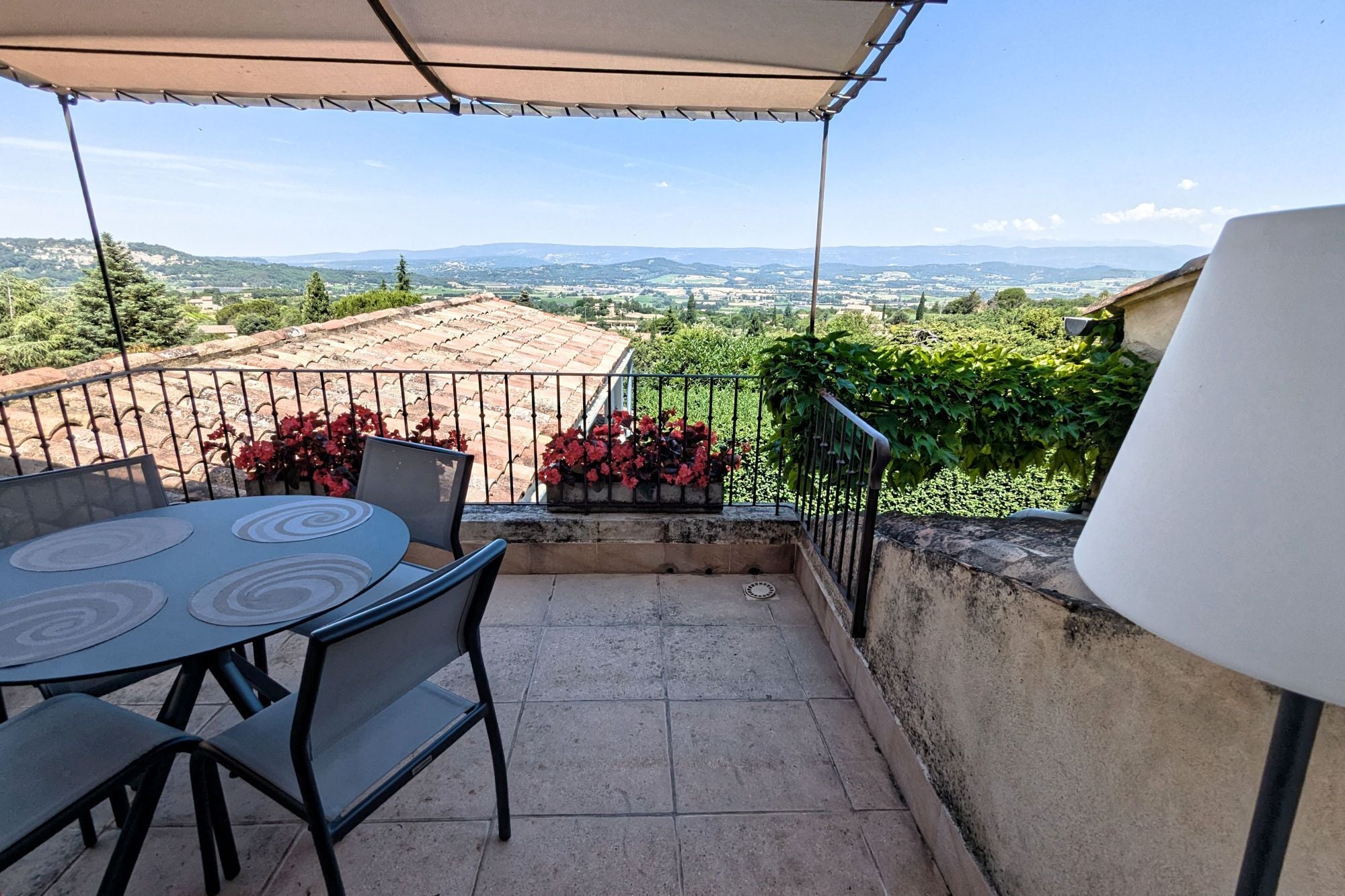 A balcony with a table and chairs, a view of a cityscape, and a railing.