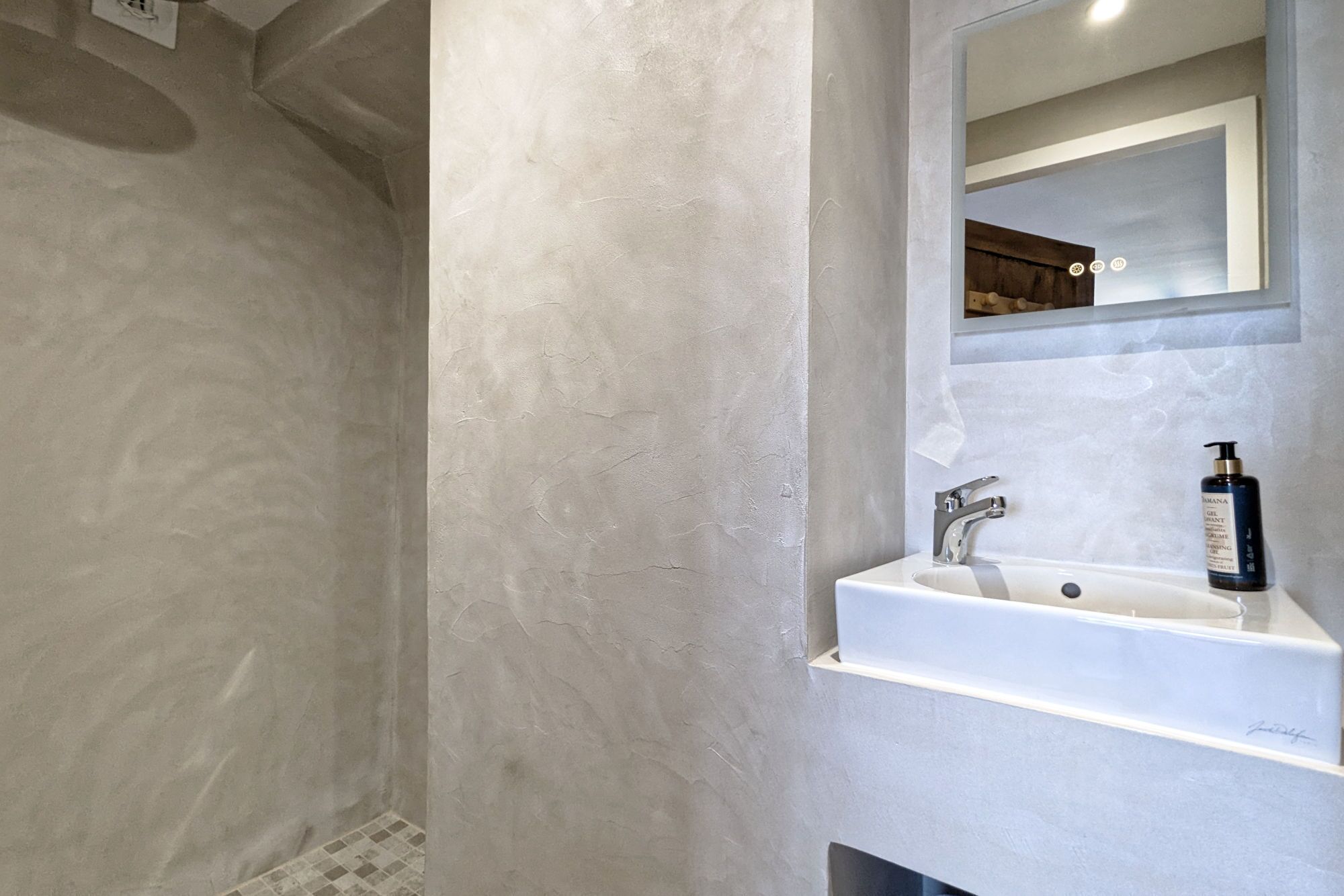 A bathroom with a large mirror, a sink, and a shower area.