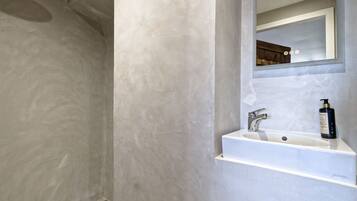A bathroom with a large mirror, a sink, and a shower area.