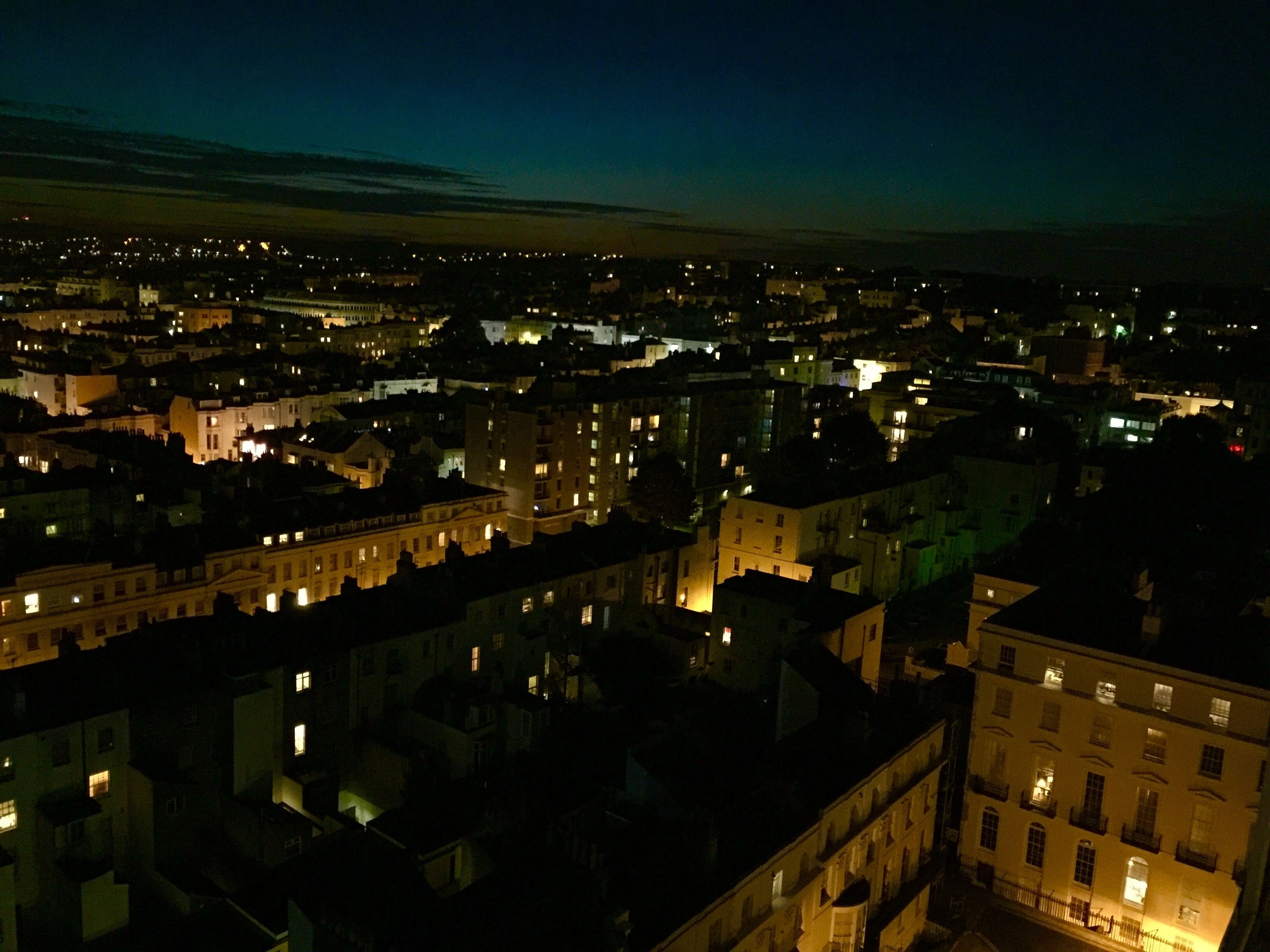 A nighttime cityscape with illuminated buildings and a river.