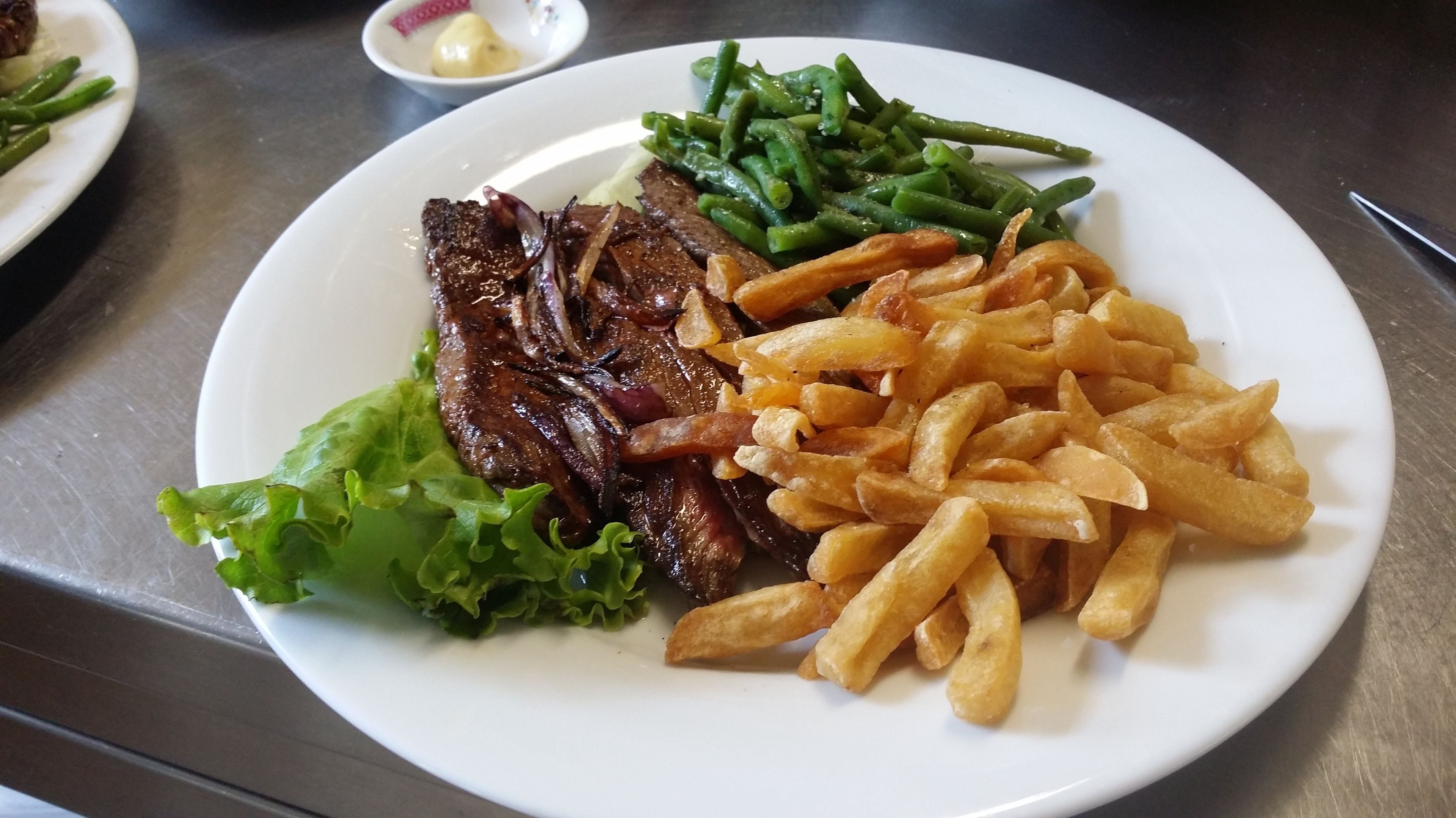 A plate with steak, green beans, fries, and lettuce.