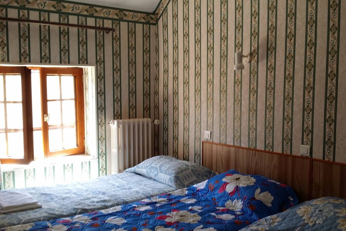 A bedroom with a wooden headboard, a radiator, and a window with curtains.