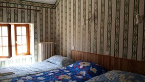 A bedroom with a wooden headboard, a radiator, and a window with curtains. - A La Vieille Halle (Souppes-sur-Loing)