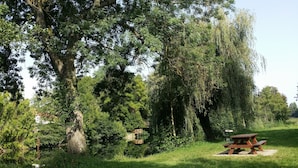 Une table de pique-nique dans un parc où les arbres sont nombreux et où se trouve un petit pont.