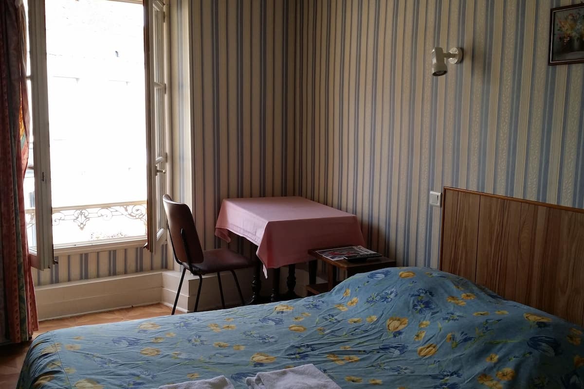 A bedroom with a bed, a desk, and a chair.