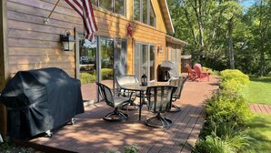 A wooden deck with outdoor furniture, a barbecue grill, and an American flag. - Beautiful four season chalet in northern Wisconsin Lakeshore (Siren)