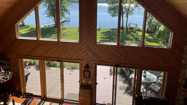 A cabin with large windows offering views of a lake and dock. Inside, there is a wooden table and a bench. - Beautiful four season chalet in northern Wisconsin Lakeshore (Siren)
