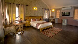 A hotel room with a bed, bedside tables, a TV, a small table with a vase, and a chair.
