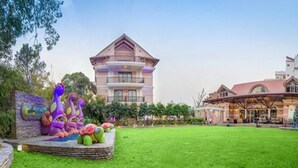 A hotel with a large lawn, a building with a red roof, and a mural of colorful sea creatures.