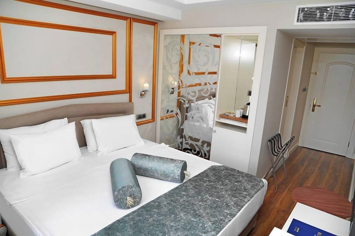 Ein Hotelzimmer mit Bett, Spiegel, Kleiderschrank und Tür.