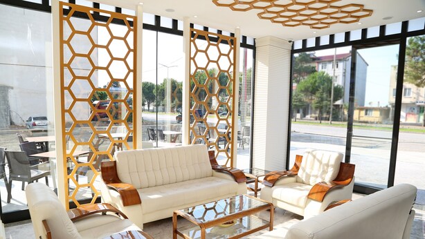 A modern interior with a white sofa, leather armchairs, and a glass coffee table. - Kubalic Hotel (Ordu)