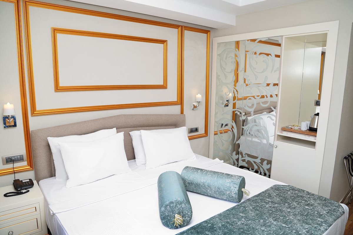A hotel room with a bed, bedside table, lamp, and a mirror.