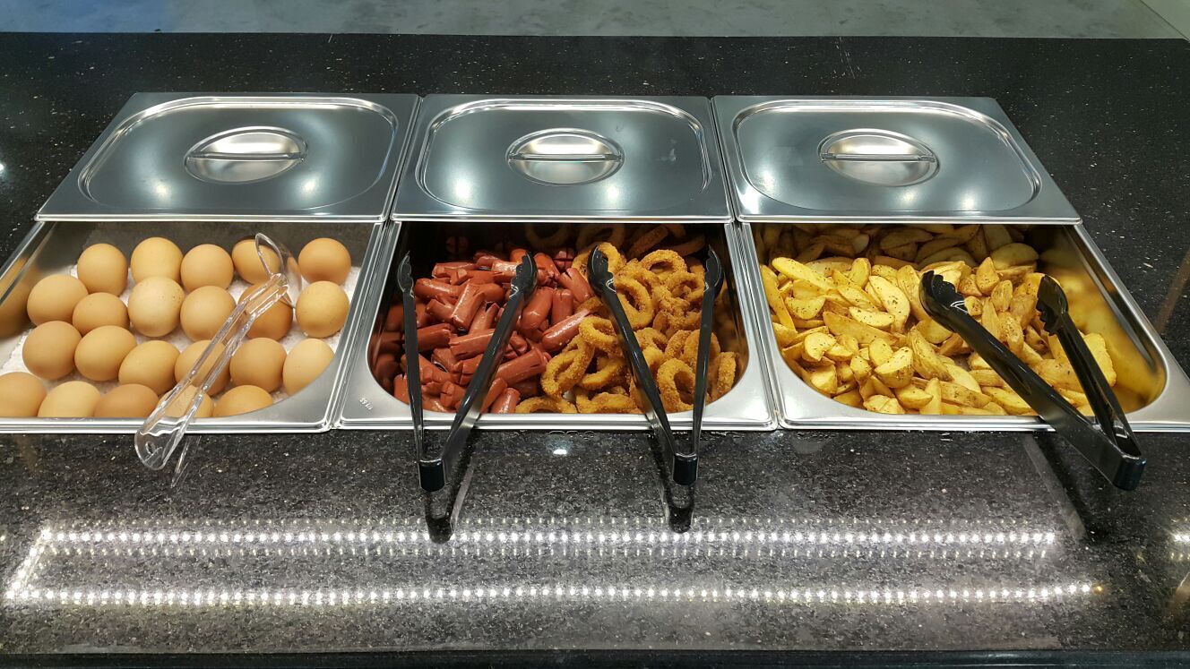 A buffet with three sections: eggs, sausages, and potato wedges.