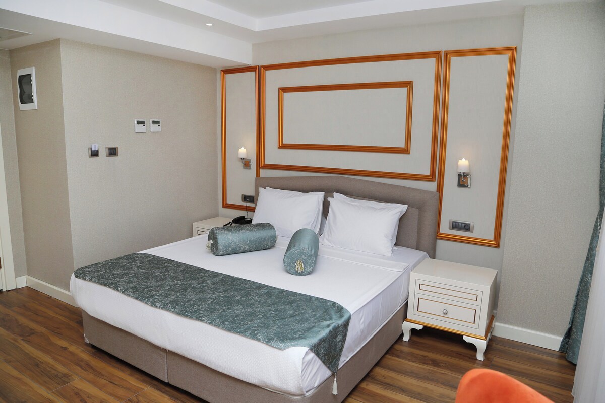 Una habitación de hotel con una cama grande, mesitas de noche y una silla.