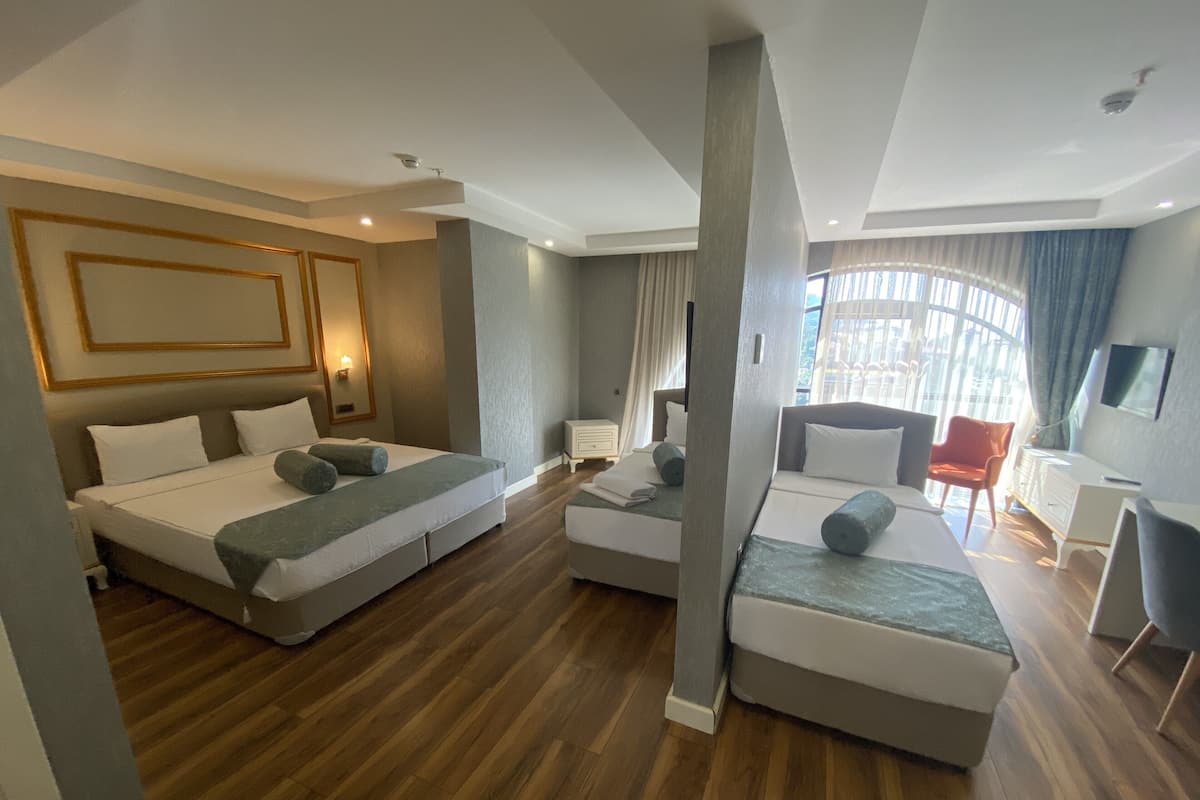 A modern hotel room with two beds, a sitting area, and a TV.
