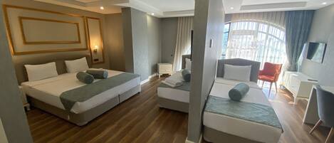 Quarto de hotel moderno com duas camas, área de estar e televisão.