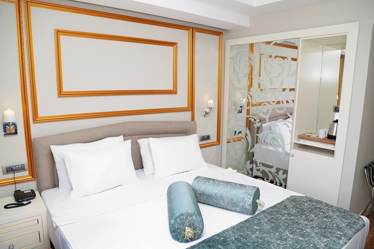 A hotel room with a bed, bedside table, lamp, and a mirror.