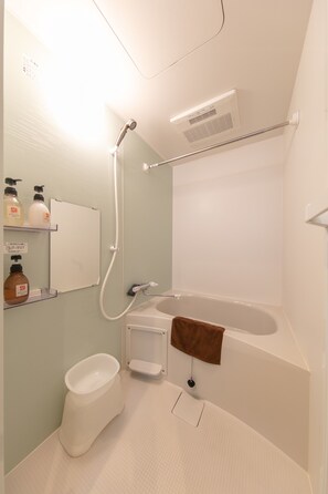 Een bad/douchecombinatie, een diep bad, designer toiletartikelen