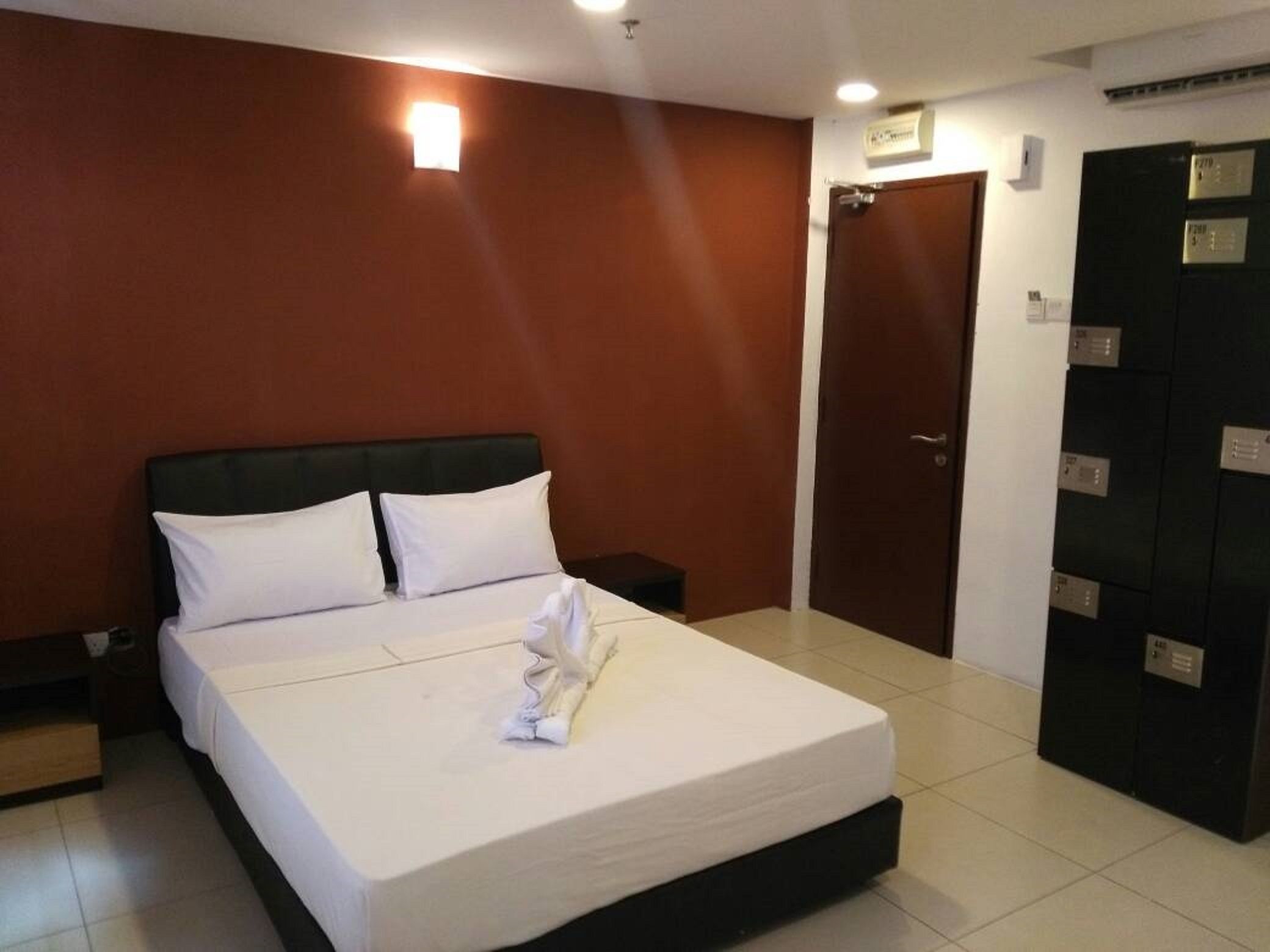 A hotel room with a bed, a nightstand, a wardrobe, and a door.
