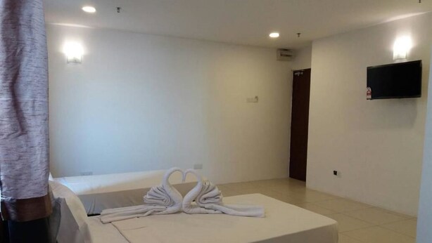 A hotel room with a bed, a TV mounted on the wall, and a door. - T Hotel Ipoh (Ipoh)
