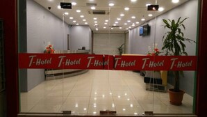 A hotel reception area with a red "Welcome" mat, a reception desk, and a potted plant. - T Hotel Ipoh (Ipoh)