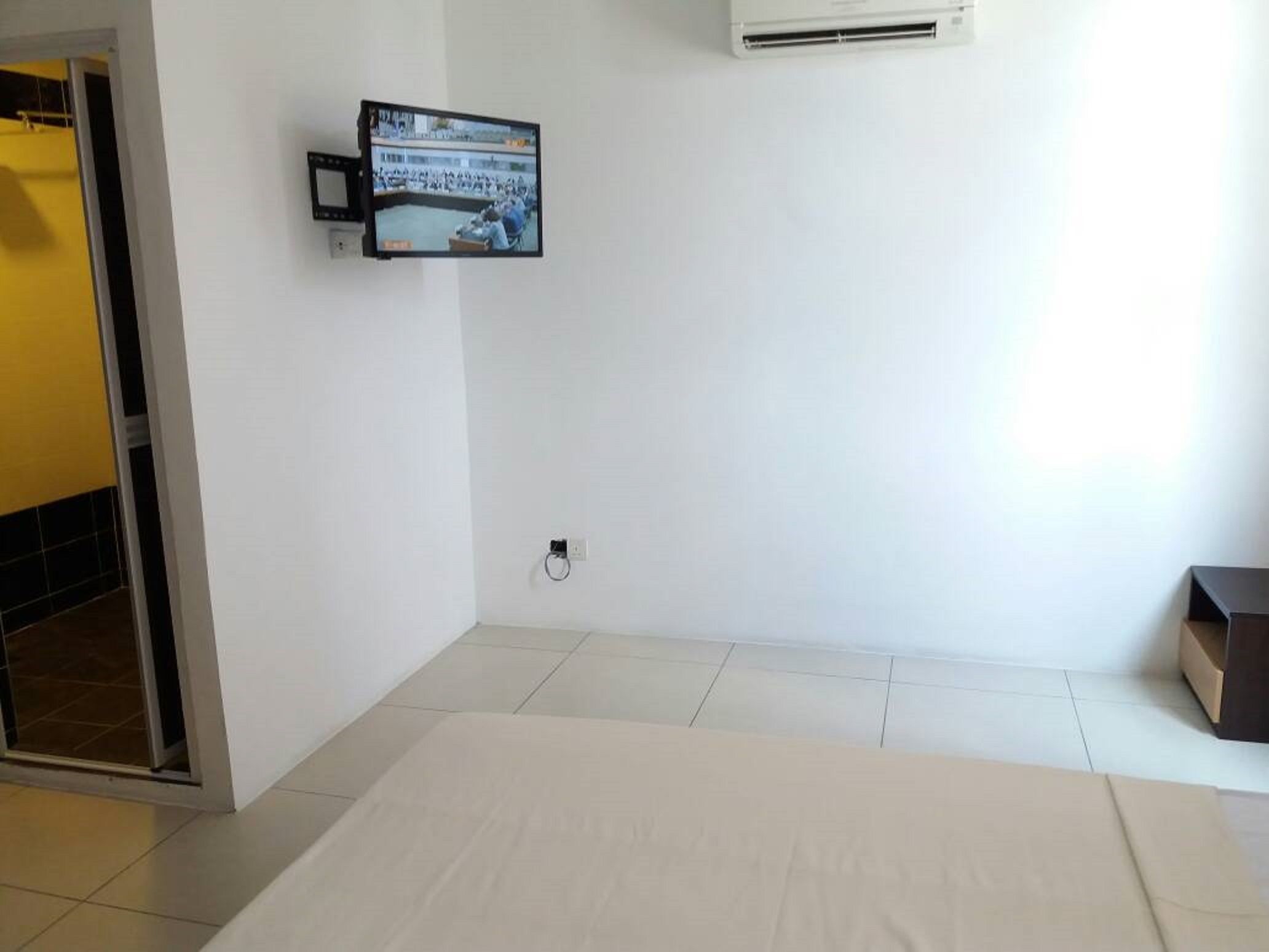A hotel room with a bed, a television mounted on the wall, and a window.