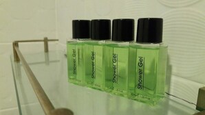 Four bottles of shower gel on a glass shelf in a bathroom. - T Hotel Ipoh (Ipoh)