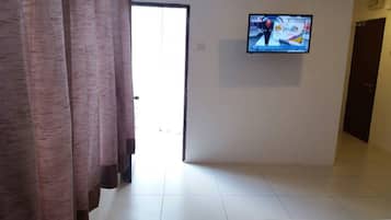A hotel room with a bed, a television mounted on the wall, and a door leading to the outside.