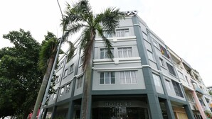 Um hotel de vários andares com design moderno, exibindo uma placa chamativa com a inscrição 'HOTEL 99' na entrada.