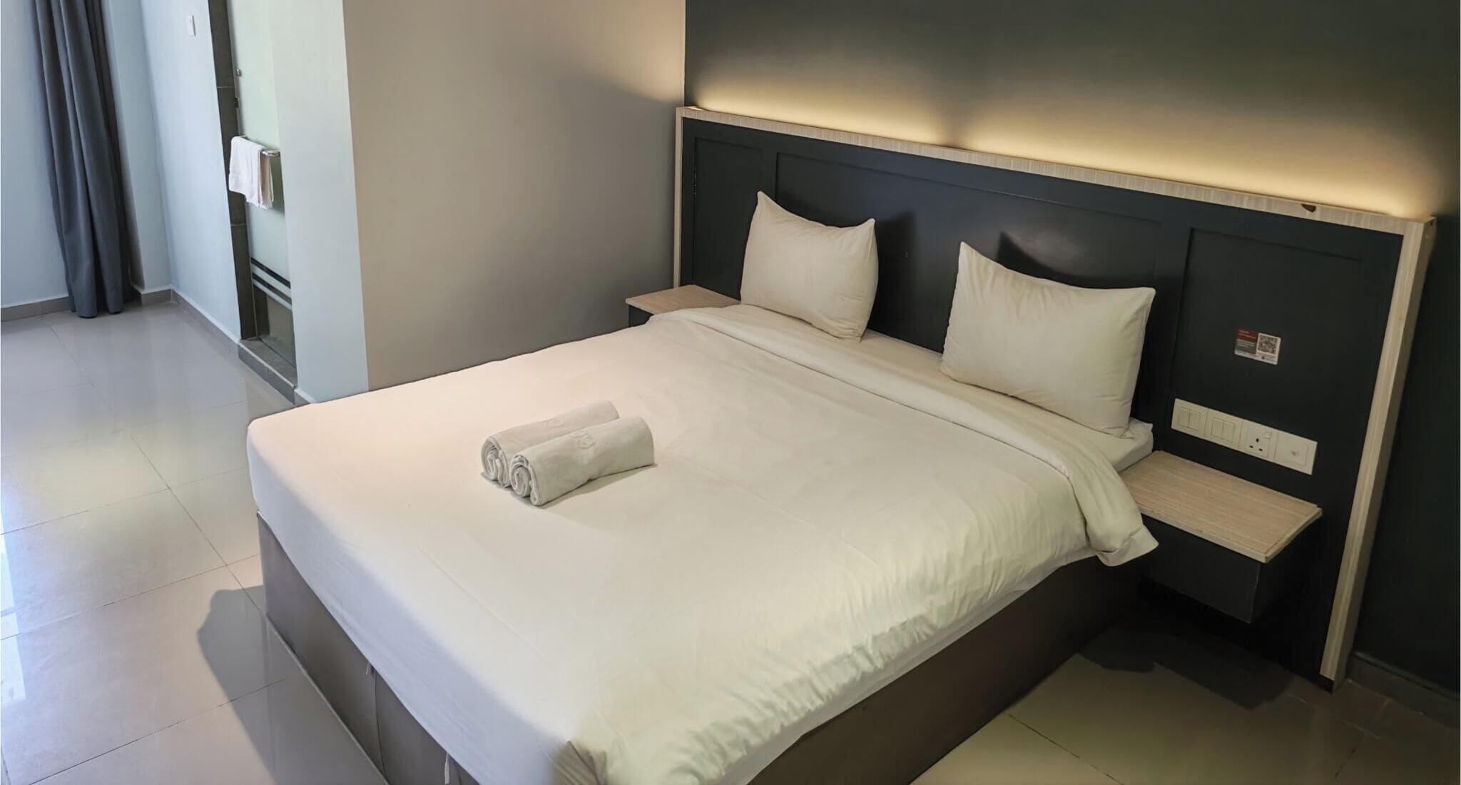 Habitación de hotel con una cama grande, dos mesitas de noche y un cabecero con iluminación integrada.