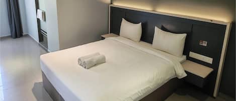 Habitación de hotel con una cama grande, dos mesitas de noche y un cabecero con iluminación integrada.