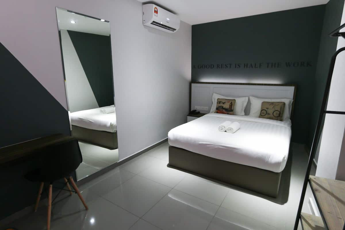 Une chambre d’hôtel moderne, dotée d’un grand lit, d’un bureau et d’un miroir.
