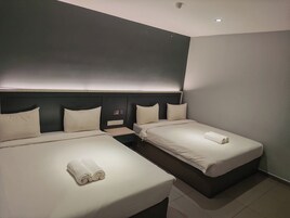 A hotel room with two beds, a dark headboard, and a small bedside table with a lamp.
