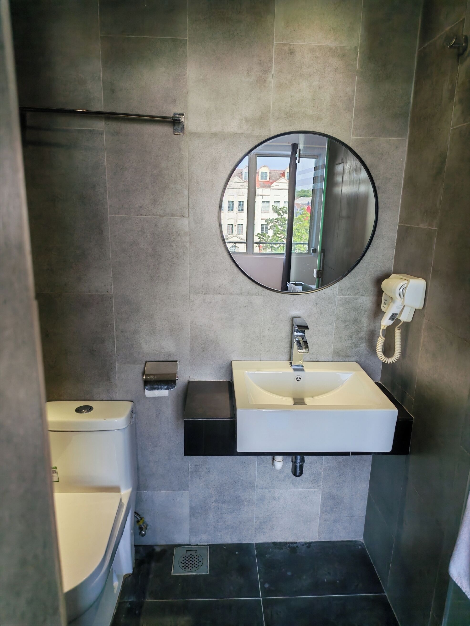Un baño con inodoro, lavamanos, espejo y teléfono.
