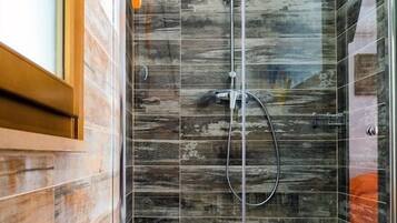 A glass-enclosed shower with a wooden wall panel design, a bench, and a tiled floor.