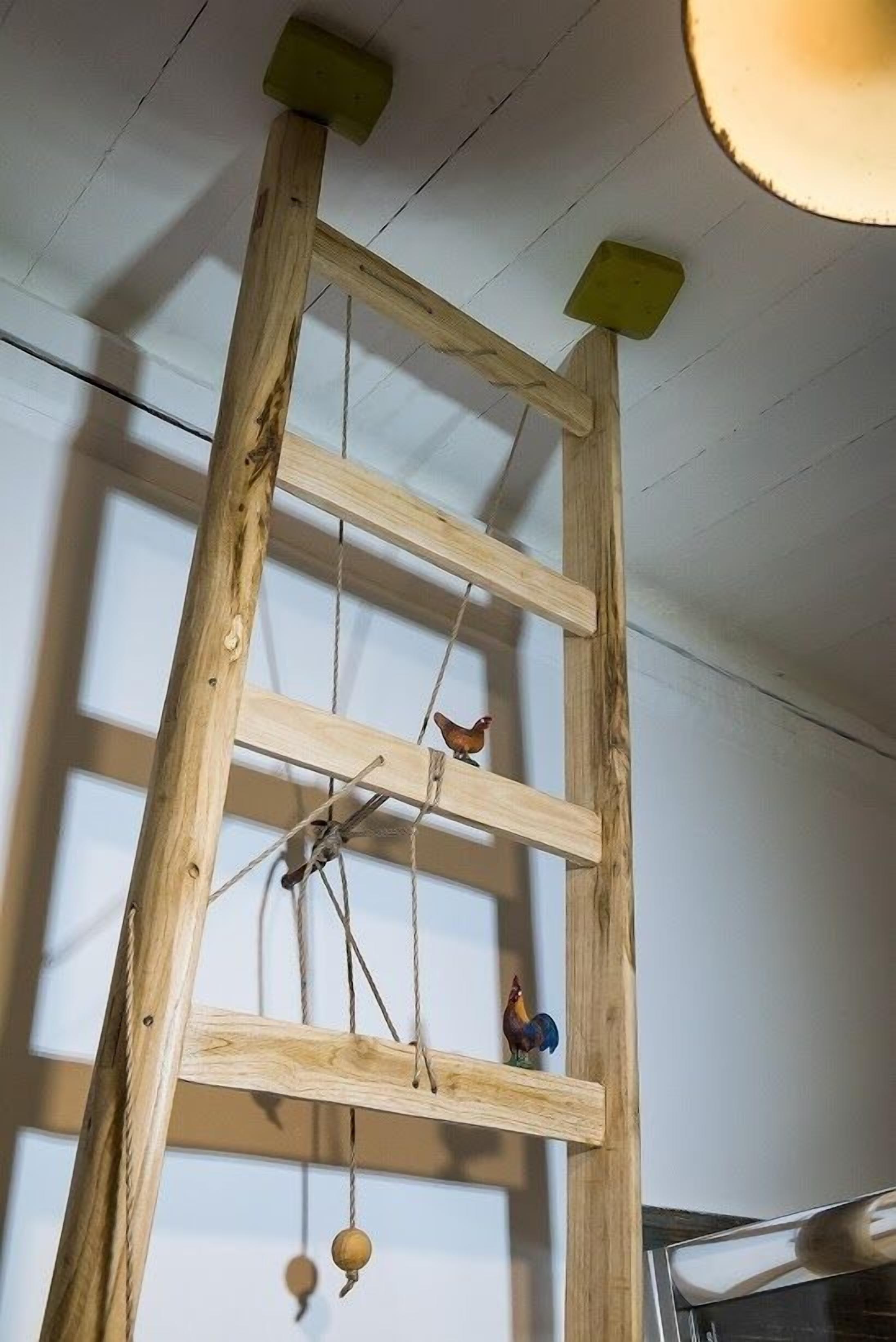 Una escalera de madera con dos pequeñas figuras colgadas.