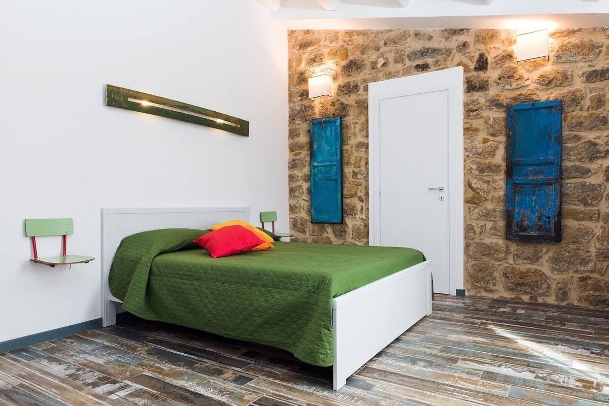 Un dormitorio con pared de piedra, una puerta blanca y dos puertas azules.