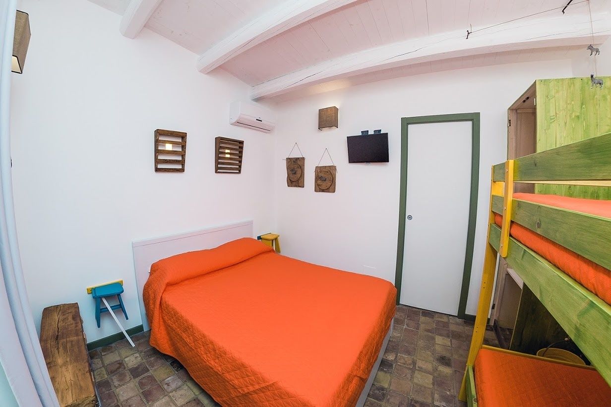 Una habitación pequeña y acogedora con una cama individual, un banco de madera y una puerta.