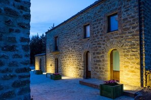 A stone building with arched doorways and windows, illuminated by warm lighting. - La Quercia e l'Asino (Piazza Armerina)
