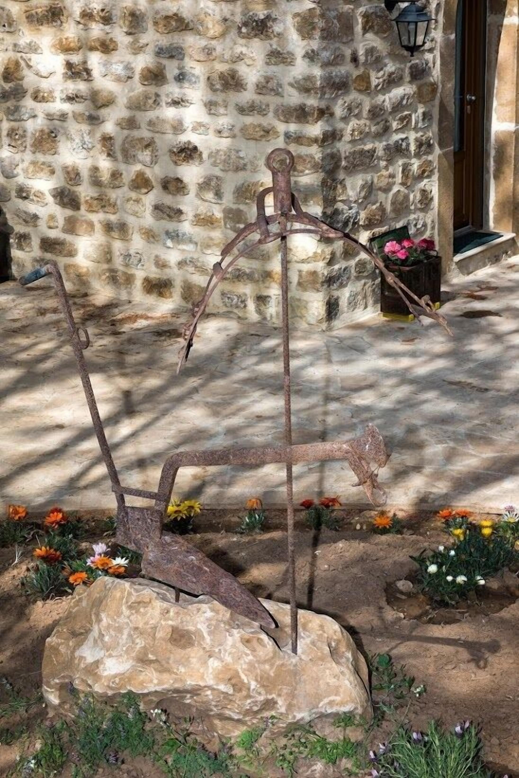 A rustic outdoor area with a stone wall, a metal sculpture, and a potted plant.