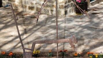 A rustic outdoor area with a stone wall, a metal sculpture, and a potted plant.