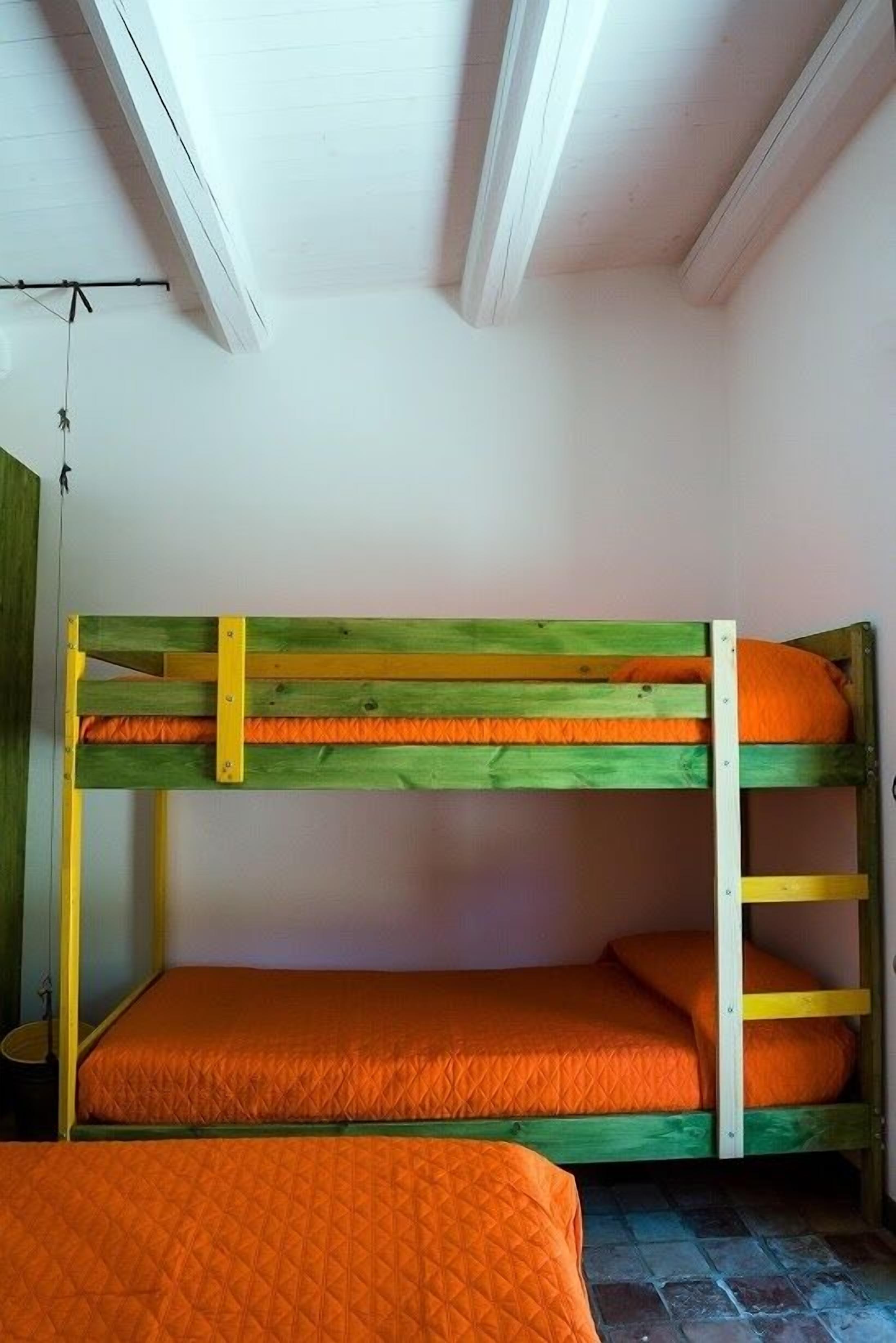 A bunk bed with two levels, each with an orange quilted mattress.