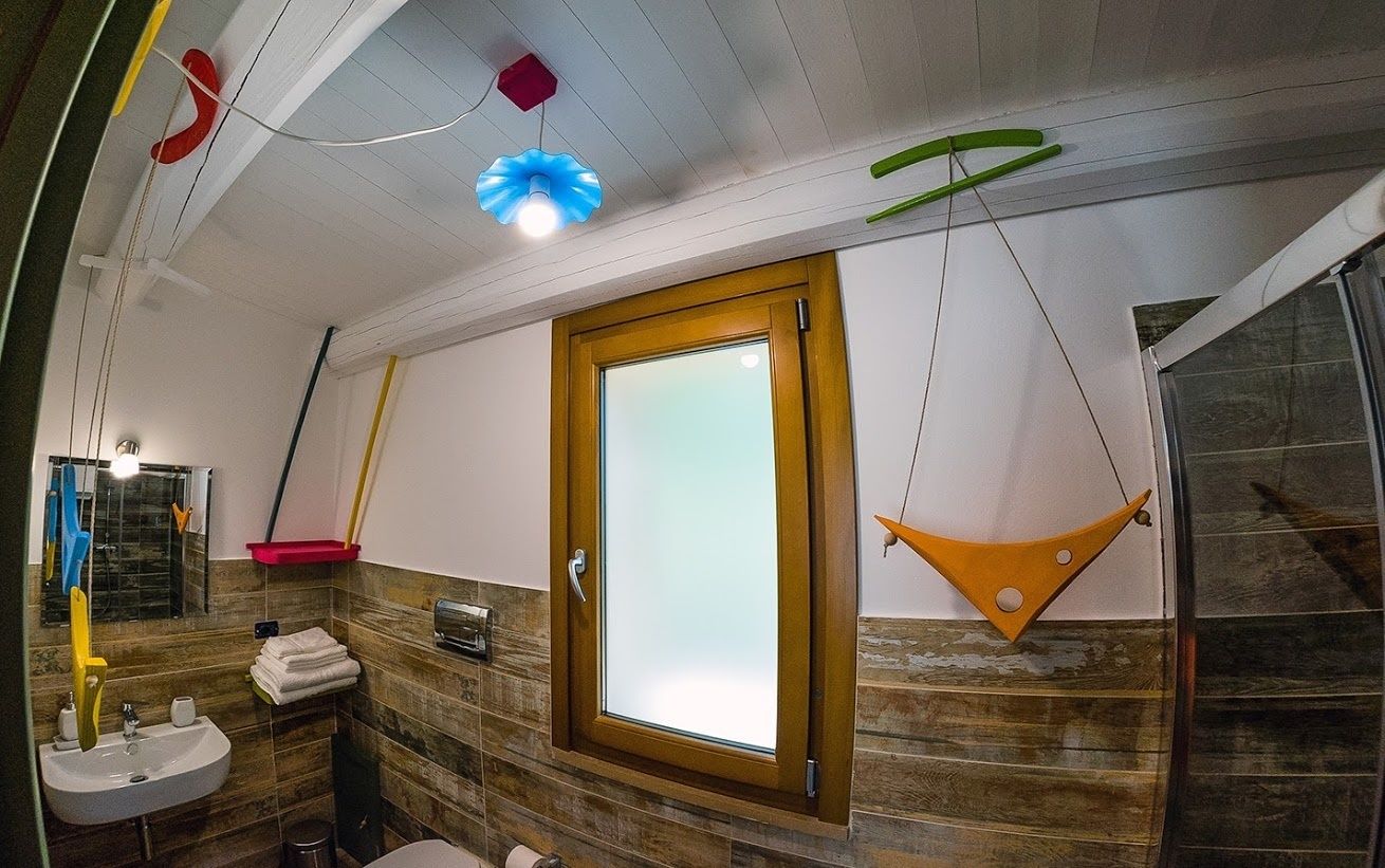 Un baño con tocador de madera, un lavabo, un espejo y una ventana con puerta de vidrio esmerilado.