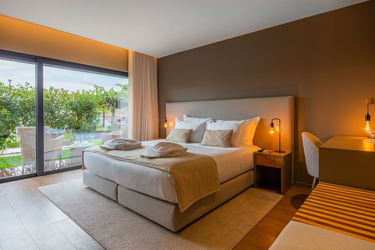 Une chambre moderne avec un grand lit, des tables de chevet et une vue sur la verdure.