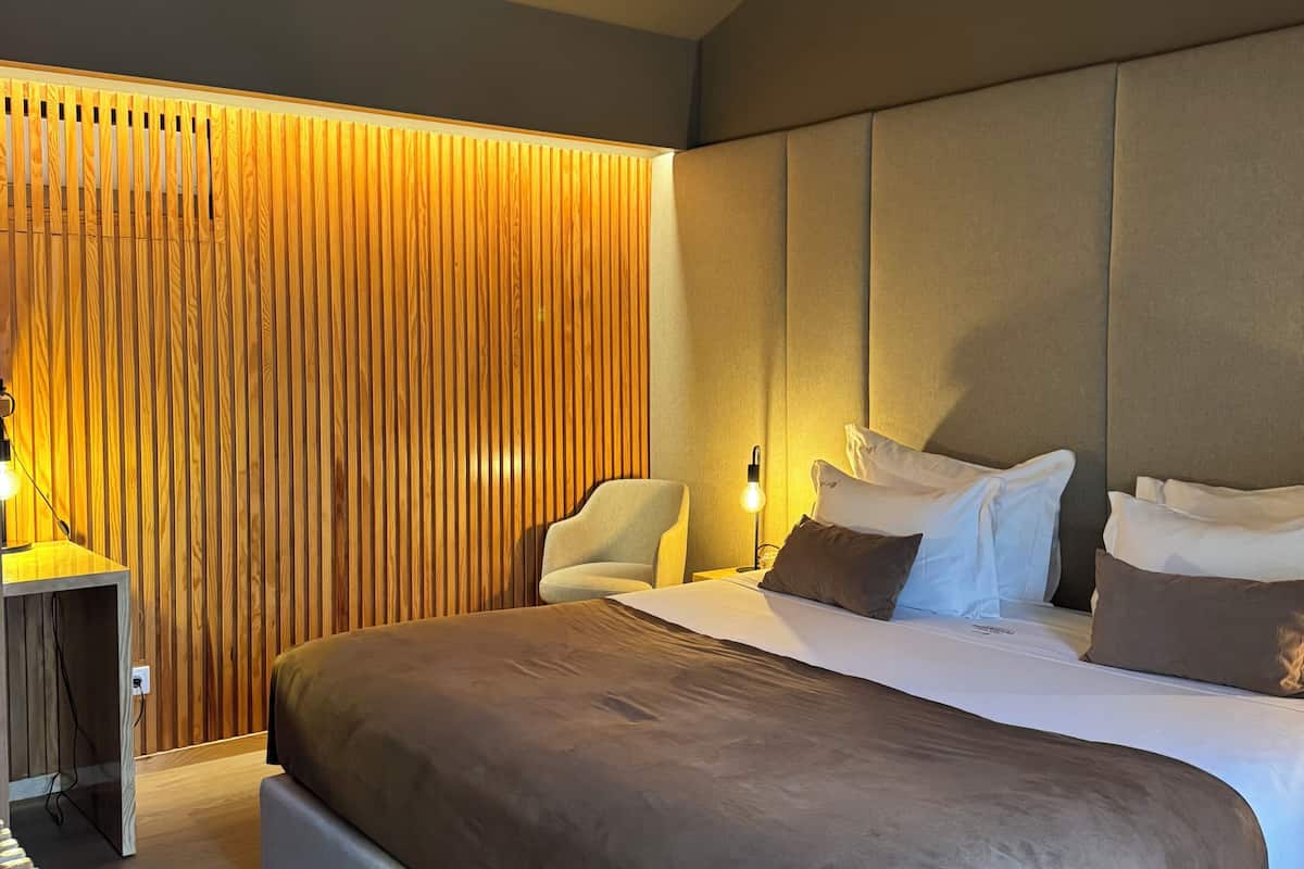 Une chambre d’hôtel moderne dotée d’un grand lit, d’un coin salon et d’un mur décoratif en bois.