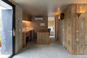 Uma cozinha moderna com ilha central, eletrodomésticos embutidos e uma parede de pedra ao fundo.