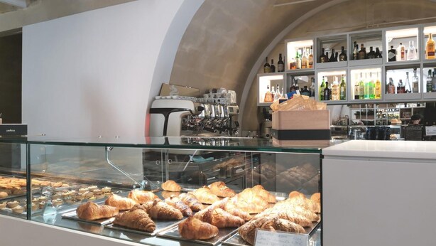 A bakery display case with pastries and a coffee bar in the background. - Vicolo Fiore Affittacamere (Matera)