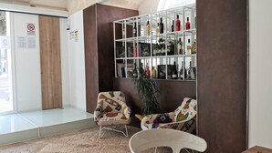 A lobby with a seating area, a bookshelf with various items, and a door with a sign. - Vicolo Fiore Affittacamere (Matera)